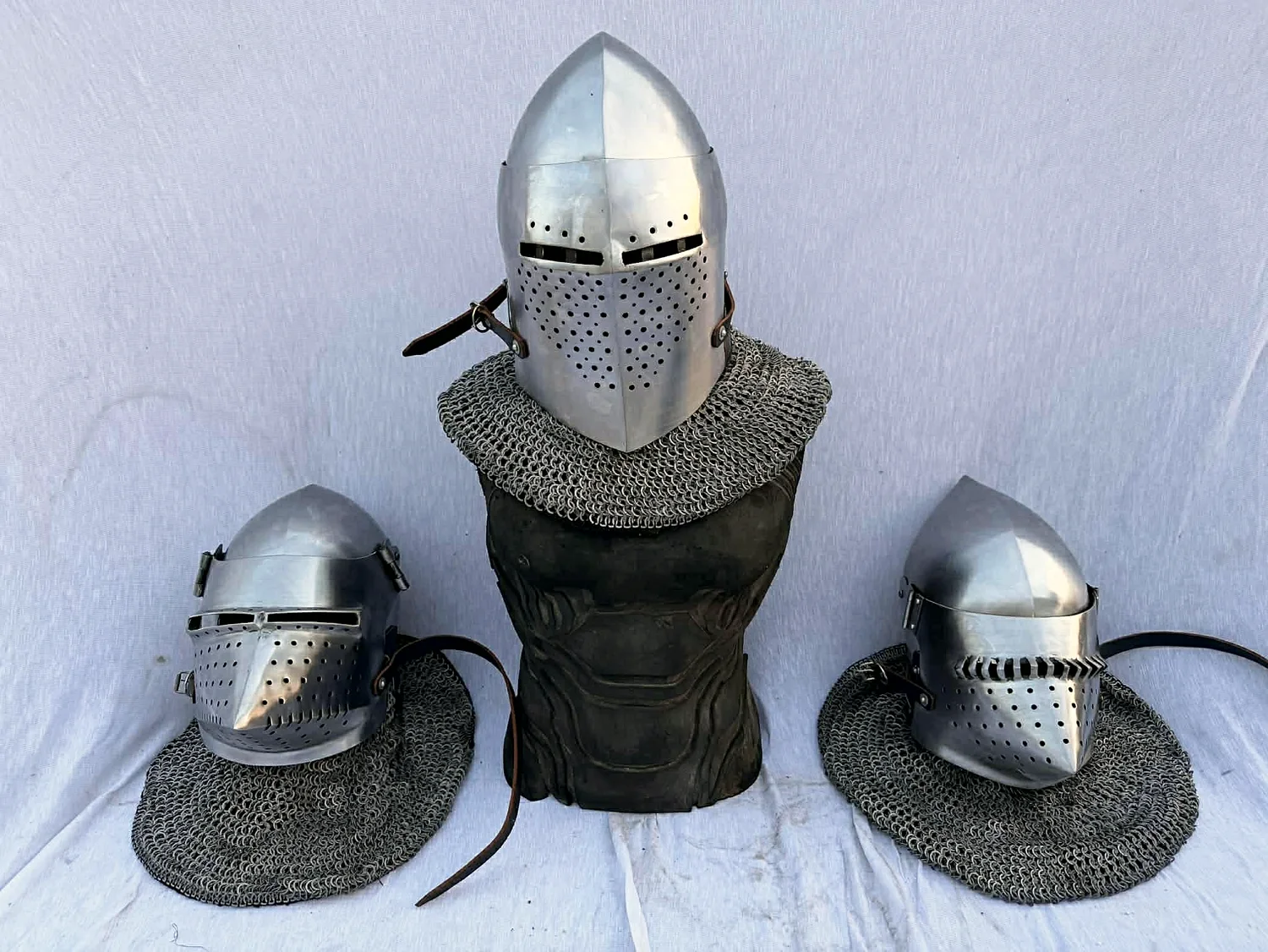 Three bascinets — two hounskulls flanking a Spoleto, all with riveted mail aventails